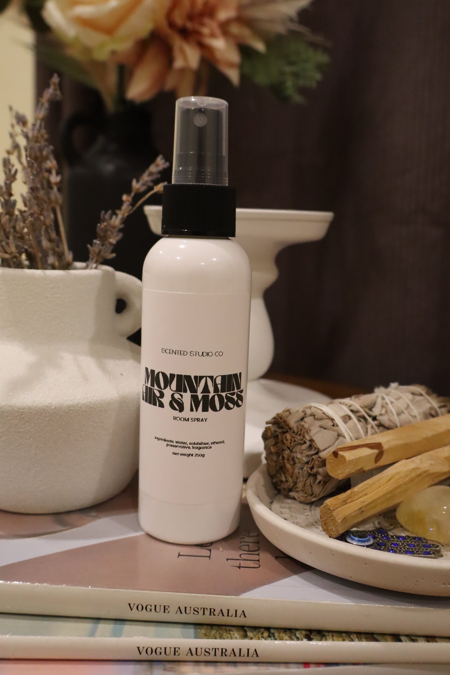 White spray bottle with black text on a magazine and decorative items