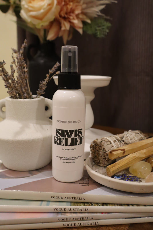 White spray bottle labeled 'SINUS RELIEF' on a surface with books and decorative items.