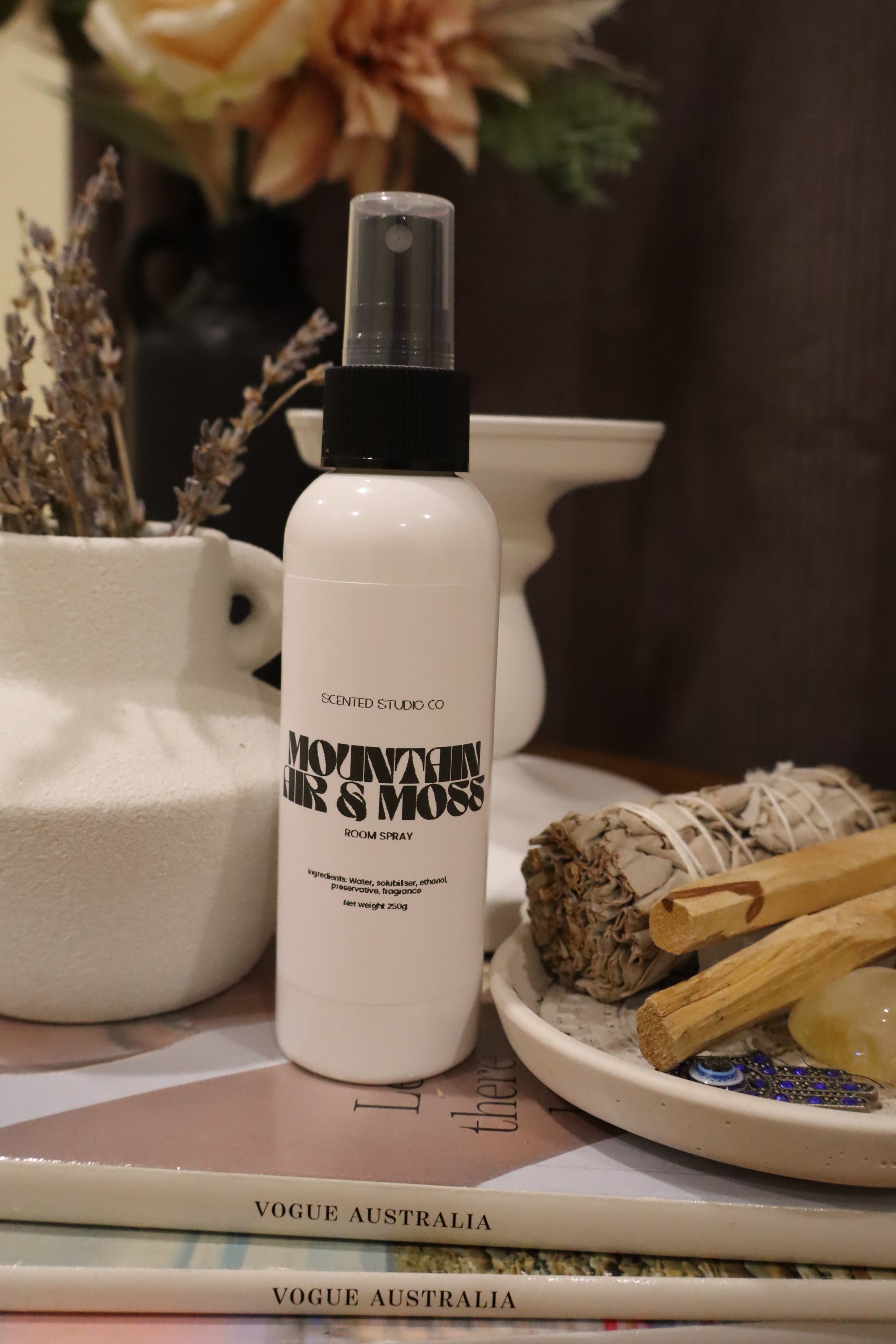 White spray bottle with black text on a magazine and decorative items