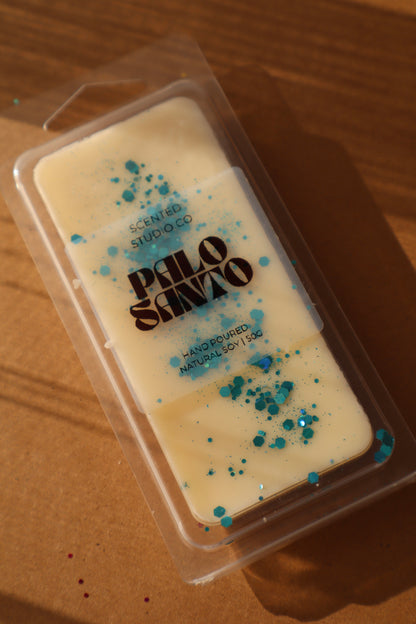 Scented wax bar in a clear packaging with 'Palo Santo' branding on a wooden surface.