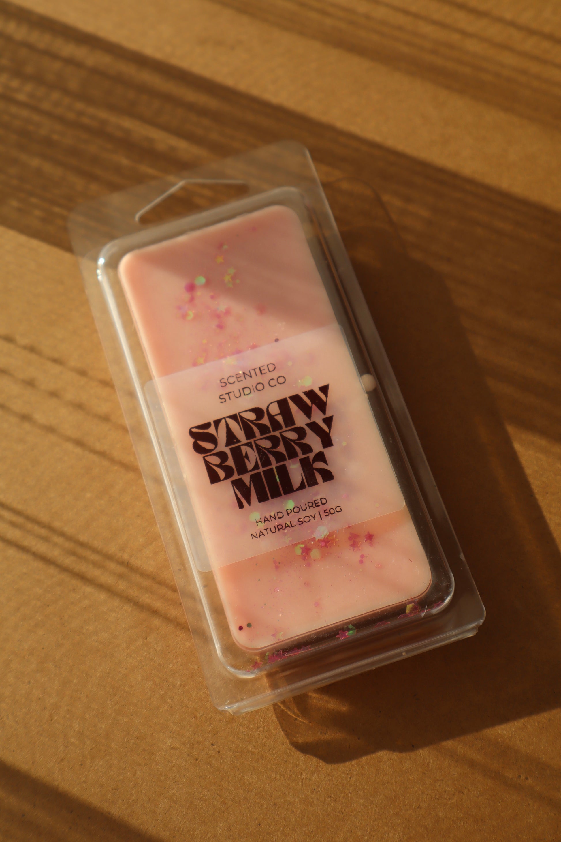 Packaged strawberry milk wax melt on a wooden surface